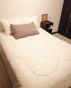 - un grand lit blanc avec un oreiller marron dans l'établissement Apartamento zona 4 Guatemala y Parqueo, à Guatemala