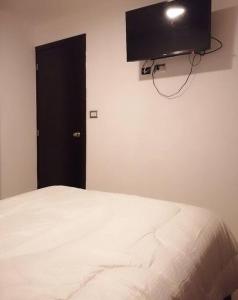 - une chambre avec un lit et une télévision murale dans l'établissement Apartamento zona 4 Guatemala y Parqueo, à Guatemala