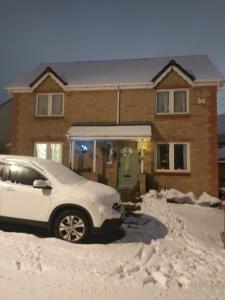 Un coche aparcado delante de una casa cubierta de nieve en Homely Haven, Dunfermline, en Dunfermline