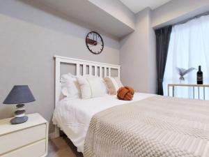 a bedroom with a white bed and a clock on the wall at S22新宿最中心 東新宿站5分-Shinjuku center 5 mins to Station, Max 3P 直达直达新宿 涉谷 表参道 池袋 上野 代代木 银座 原宿 in Tokyo