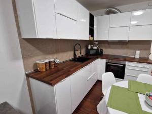 cocina con armarios blancos y encimera de madera en La Casa di Vale Muse en Trento