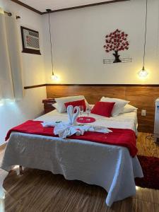 1 dormitorio con 1 cama grande con sábanas rojas y blancas en Pousada Sabor da Serra, en Visconde De Maua