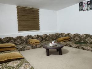 ein Wohnzimmer mit einem Sofa und einem Tisch mit einem Kuchen darauf in der Unterkunft Rousan House in Um Qeis