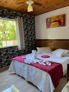1 dormitorio con 1 cama grande con manta roja en Pousada Sabor da Serra, en Visconde De Maua