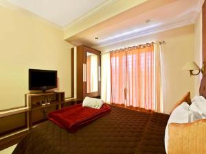 a hotel room with a bed and a flat screen tv at Sky High Cottages in Ooty