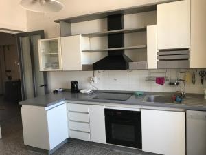 uma cozinha com armários brancos e um lavatório em Appartamento davanti al mare em Savona