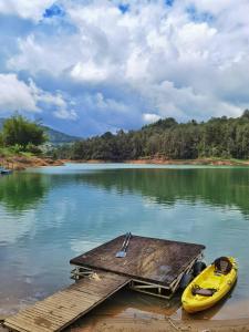 een gele boot naast een steiger aan een meer bij Descanso Bajo La Piedra Del Peñol in Guatapé