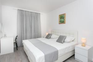 a white bedroom with a white bed and a window at Apartment Dupčić in Dubrovnik