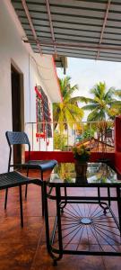 Habitación con mesa, silla y palmeras. en Mitra Hostel (By The Pool), en Vagator