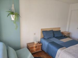 a bedroom with a blue bed and a couch at Apartamento confort urzaiz vigo. in Vigo