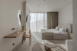 a white hotel room with a bed and a mirror at Sfumato Rooms in Odesa