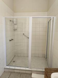 a shower with a glass door in a bathroom at Country Village in Graaff-Reinet