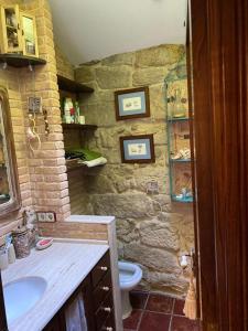 een stenen badkamer met een wastafel en een toilet bij Casa Celsa cerca del mar in Baiona