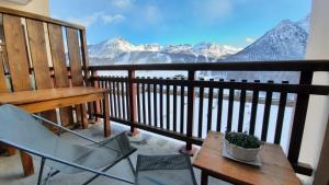 a table and a chair on a balcony with mountains at Le COCON DES NEIGES MONTGENEVRE in Montgenèvre