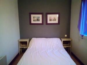 a bedroom with a white bed and two tables at Vachement bien ! in Saint-Nicolas-de-la-Haie