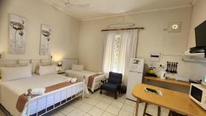 a bedroom with a bed and a desk and a chair at Country Village in Graaff-Reinet