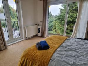a bedroom with a bed with a yellow blanket and large windows at Entire Spacious 4 Bedroom Zen House with Garden View in Bromley