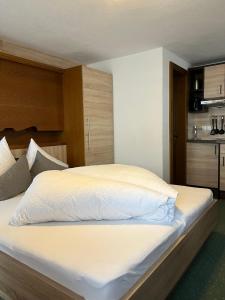 um quarto com uma cama grande e lençóis brancos em Altes Holzhaus em Sölden