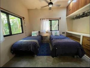twee bedden in een kamer met twee ramen bij Keiki House in Akumal