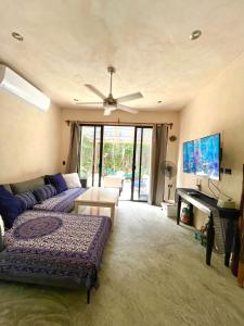 ein Wohnzimmer mit einem Sofa und einem TV in der Unterkunft Keiki House in Akumal
