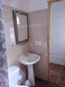 y baño con lavabo, espejo y aseo. en Apartamento Atlantida en Villa Argentina
