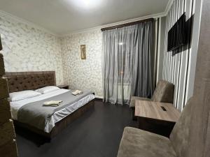 una camera da letto con un letto, un tavolo e una sedia di Baron Hotel a Vanadzor