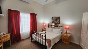 a bedroom with a bed and red curtains at Country Village in Graaff-Reinet