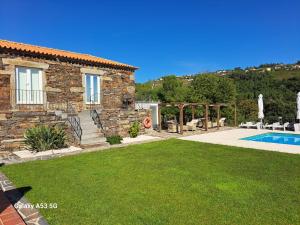 a stone house with a yard with a swimming pool at Quinta da Portelada in Peso da Régua