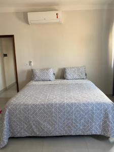 a bed with a blue comforter and two pillows at Apartamento Sorriso in Sorriso