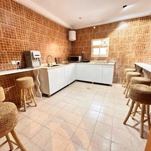 a kitchen with white cabinets and bar stools at نجد هاوس - نساء فقط Ladies Hostel in Riyadh