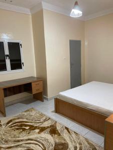 a bedroom with a bed and a desk and a television at Ace Appartement Meublé in Nouakchott
