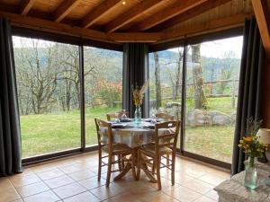 comedor con mesa, sillas y ventanas grandes en Ô Gites du Visaret, en Connac