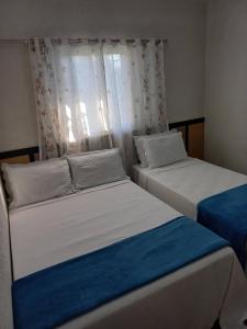 2 camas individuales en una habitación con ventana en Pousada Vilarejo de Minas en Itapeva