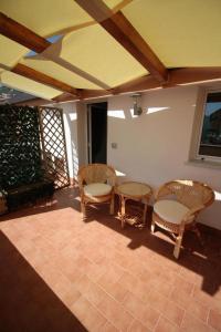 un patio con sillas de mimbre y mesas. en La Rosatea Rooms, en Monreale