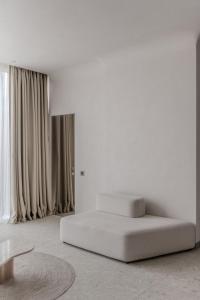 um quarto branco com uma cama e cortinas em Sfumato Rooms em Odessa