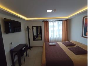 1 dormitorio con cama, mesa y escritorio en SIENA Inn HOSTAL, en Quito