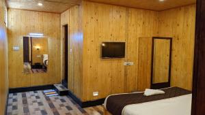 1 dormitorio con 1 cama y TV en una habitación en Loft wood house en Kodaikānāl