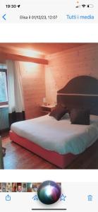 a bedroom with a large bed with a wooden headboard at Baita cavalese giardino esclusivo in Cavalese