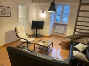 a living room with a couch and a chair and a television at Pause En Seine- Appartement en duplex in Caudebec-en-Caux