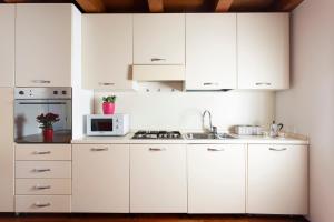 a kitchen with white cabinets and a microwave at Comodo Apt Centrale in Treviso