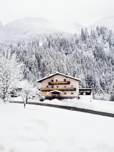 a house covered in snow with trees in the background at Haus Marinus in Jerzens