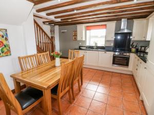 a kitchen with a wooden table and wooden chairs at Orsedd Wen Cottage in Betws-y-coed