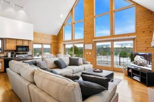 ein großes Wohnzimmer mit einem großen Sofa und Fenstern in der Unterkunft Mountain Cabin overlook Boyne near Nubs W/ Hot Tub in Harbor Springs