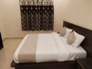 Una cama con sábanas blancas y almohadas en un dormitorio en Red Berry Resort, en Pushkar
