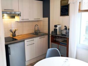 uma cozinha com armários brancos, um lavatório e uma mesa em Le Cocoon - SIPCO Immobilier - Netflix em Saint Lo