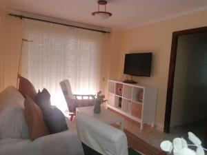 uma sala de estar com um sofá branco e uma televisão em Casa Playa de Rota em Rota