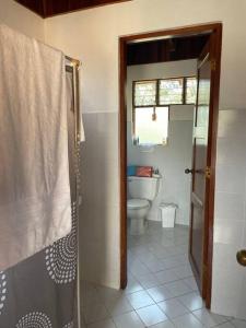 La salle de bains est pourvue de toilettes et d'une porte de douche en verre. dans l'établissement Villa Hermosa, à Playa Hermosa