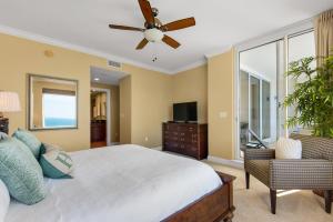 Beach Front Luxury, Amazing Views,150 - 5 Stars, 19th Floor- Indigo Condo في بينساكولا: غرفة نوم بسرير ومروحة سقف
