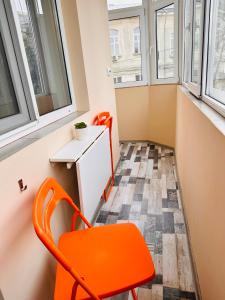 una silla naranja en una habitación pequeña con ventanas en Euro Apartment, en Bucarest