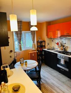 cocina con armarios naranjas, mesa y sillas en Euro Apartment, en Bucarest